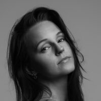 Schwarzweiß-Porträt einer jungen Frau mit langen Haaren und großen Creolen 