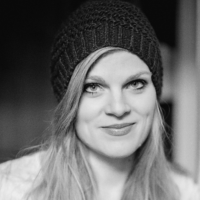 Schwarzweiß-Porträt einer jüngeren Frau mit hellen langen Haaren und einem dunklen Beanie